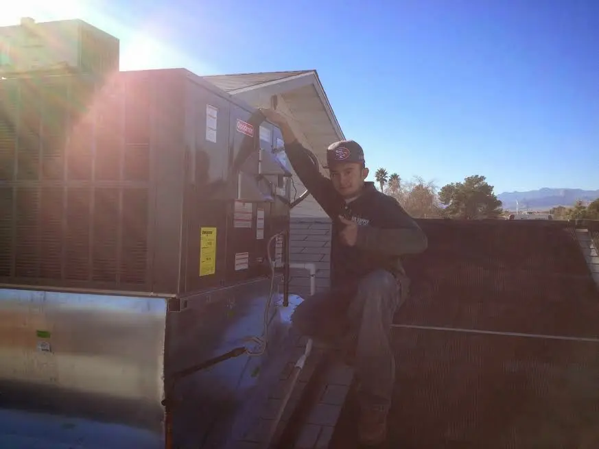 HVAC technician performing Air Duct Cleaning on a rooftop unit in Belchertown